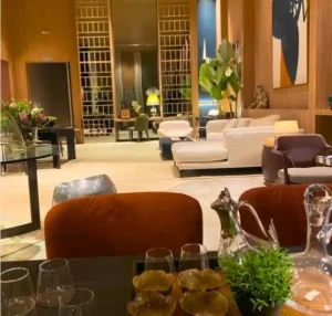 Sala com sofá bege, parede em madeira natural, obra de arte contemporânea e planta de folhas largas.