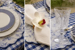 Prato azul listrado, guardanapo com orquídea e cristal transparente destacando os elementos da mesa posta.
