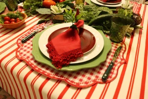 prato branco com sousplat verde e guardanapo vermelho em mesa posta italiana