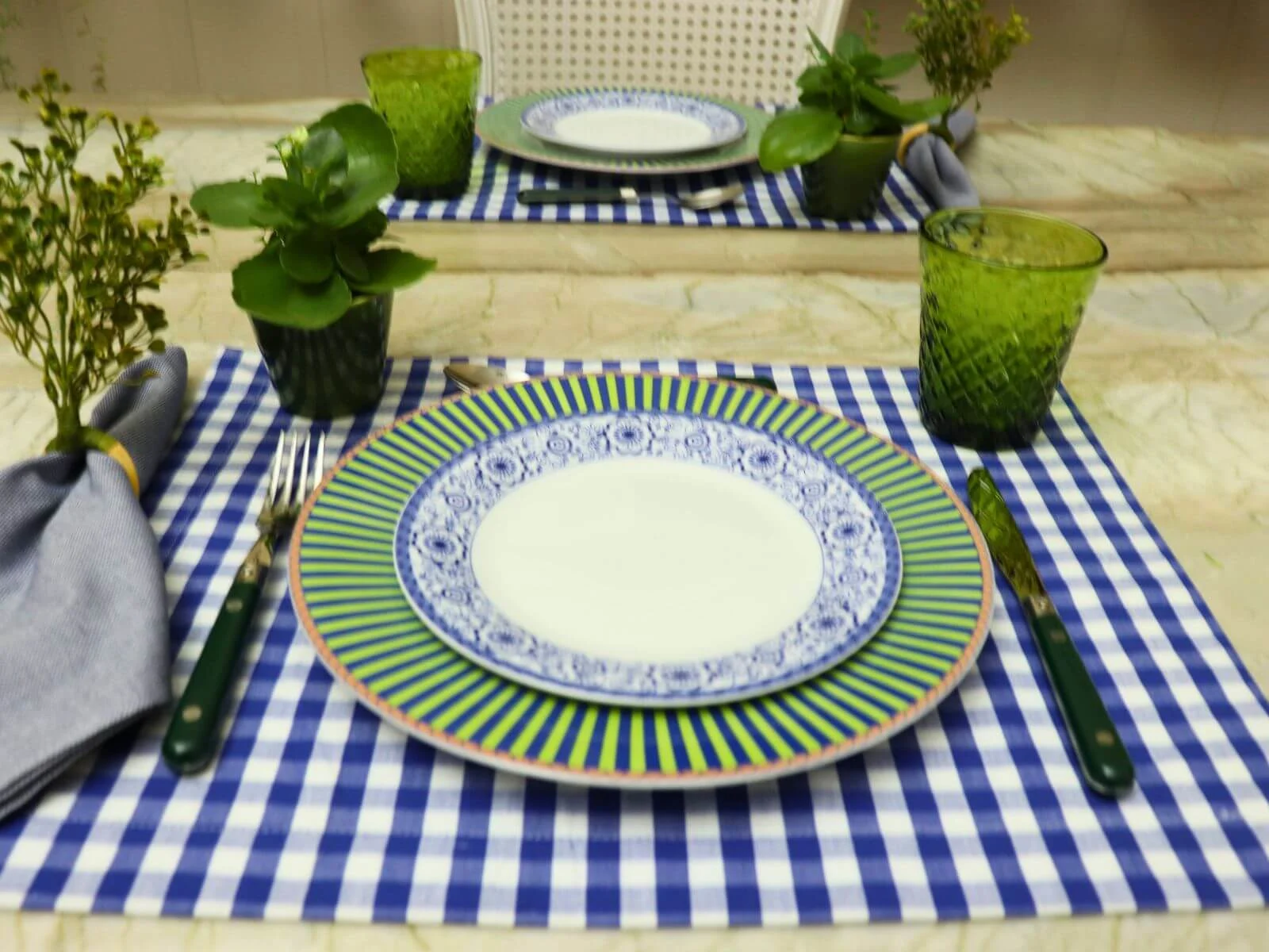 mesa-posta-com-pratos-verde-e-azul-e-copos-verdes-sobre-jogo-americano-xadrez-azul.