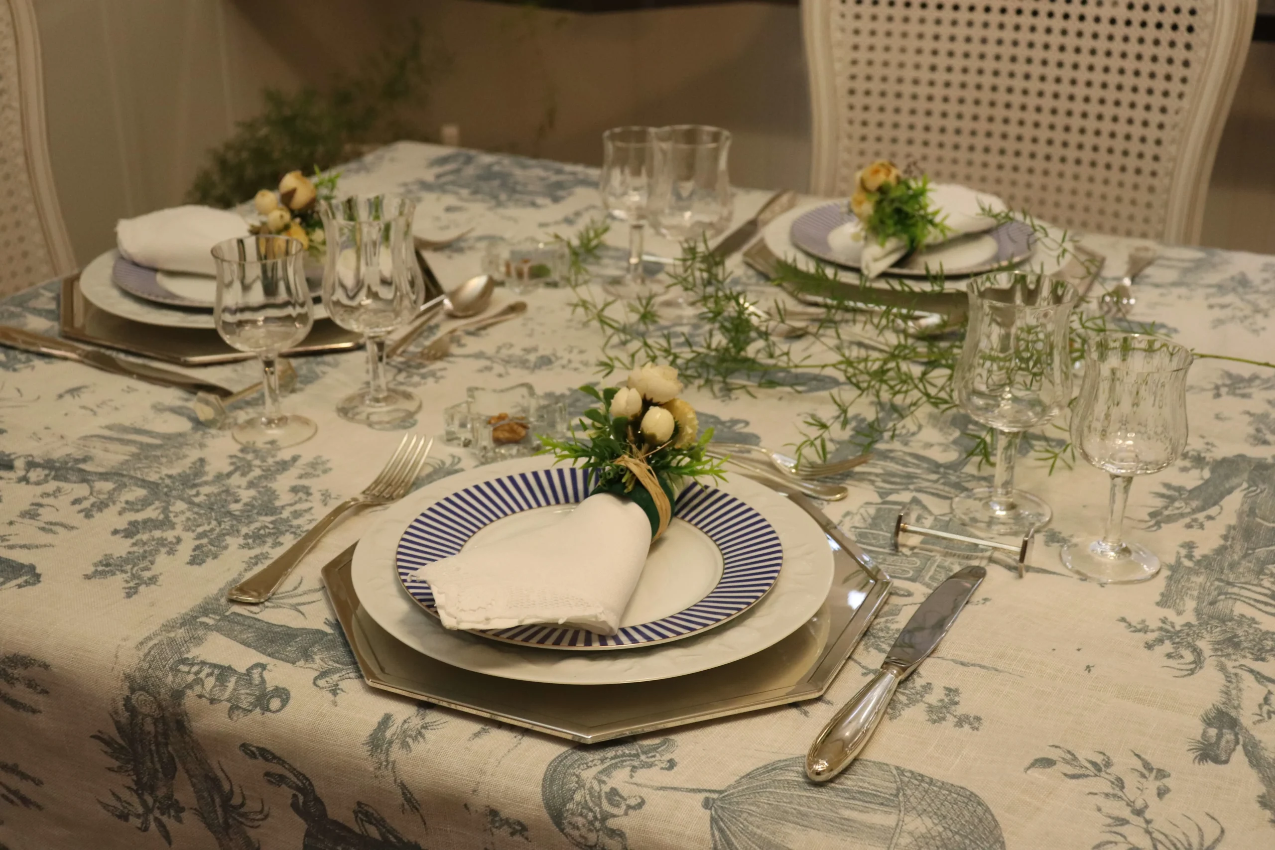 mesa-posta-elegante-para-jantar-com-louca-branca-e-azul-sousplat-dourado-e-decoracao-com-folhagens