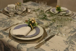 mesa-posta-sofisticada-com-toalha-estampada-loucas-classicas-e-arranjo-de-folhagem-sobre-a-mesa