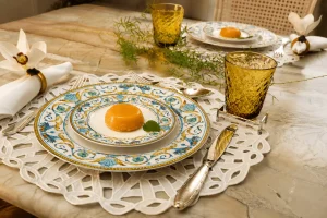 Composicao-de-mesa-posta-elegante-com-porcelana-decorada-guardanapos-brancos-folhagens-naturais-e-copos-verdes-texturizados