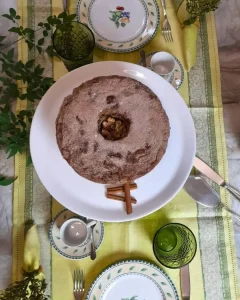 Trilho português em tons de verde servindo de base para mesa posta com bolo artesanal e louças clássicas.