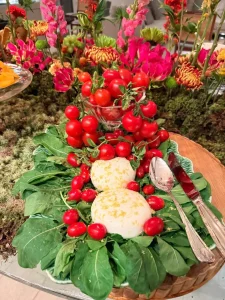 Burratas-com-tomates-cereja-sobre-folhas-verdes-integradas-a-decoracao-floral-de-mesa-para-receber-amigos