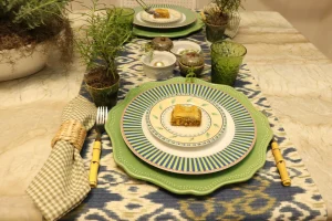 Composição de mesa posta azul e verde com sousplat verde, louça estampada e guardanapo vichy.