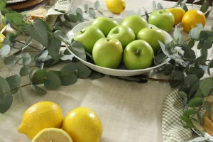 Composição natural com maçãs verdes, limões sicilianos e eucalipto em mesa posta sofisticada