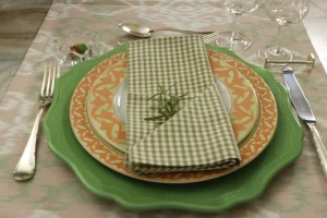 Detalhe-de-mesa-posta-com-porcelana-decorada-sousplat-verde-guardanapo-vichy-e-composicao-em-camadas.