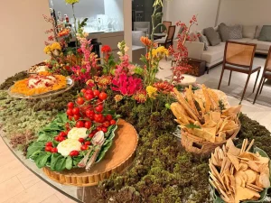 Mesa-inspirada-na-natureza-com-flores-vibrantes-burrata-tomates-cereja-e-paes-artesanais-distribuidos-sobre-musgo-natural.