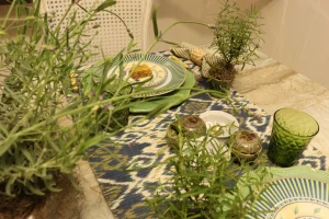 Mesa-posta-azul-e-verde-com-trilho-Ikat-lavandas-ervas-aromaticas-e-loucas-decoradas-vista-em-perspectiva-