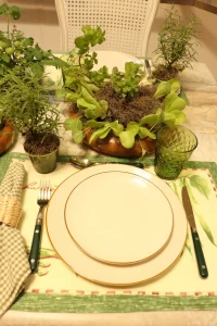 Mesa posta com ervas aromáticas, hortaliças e louças neutras em composição inspirada na natureza e na horta doméstica