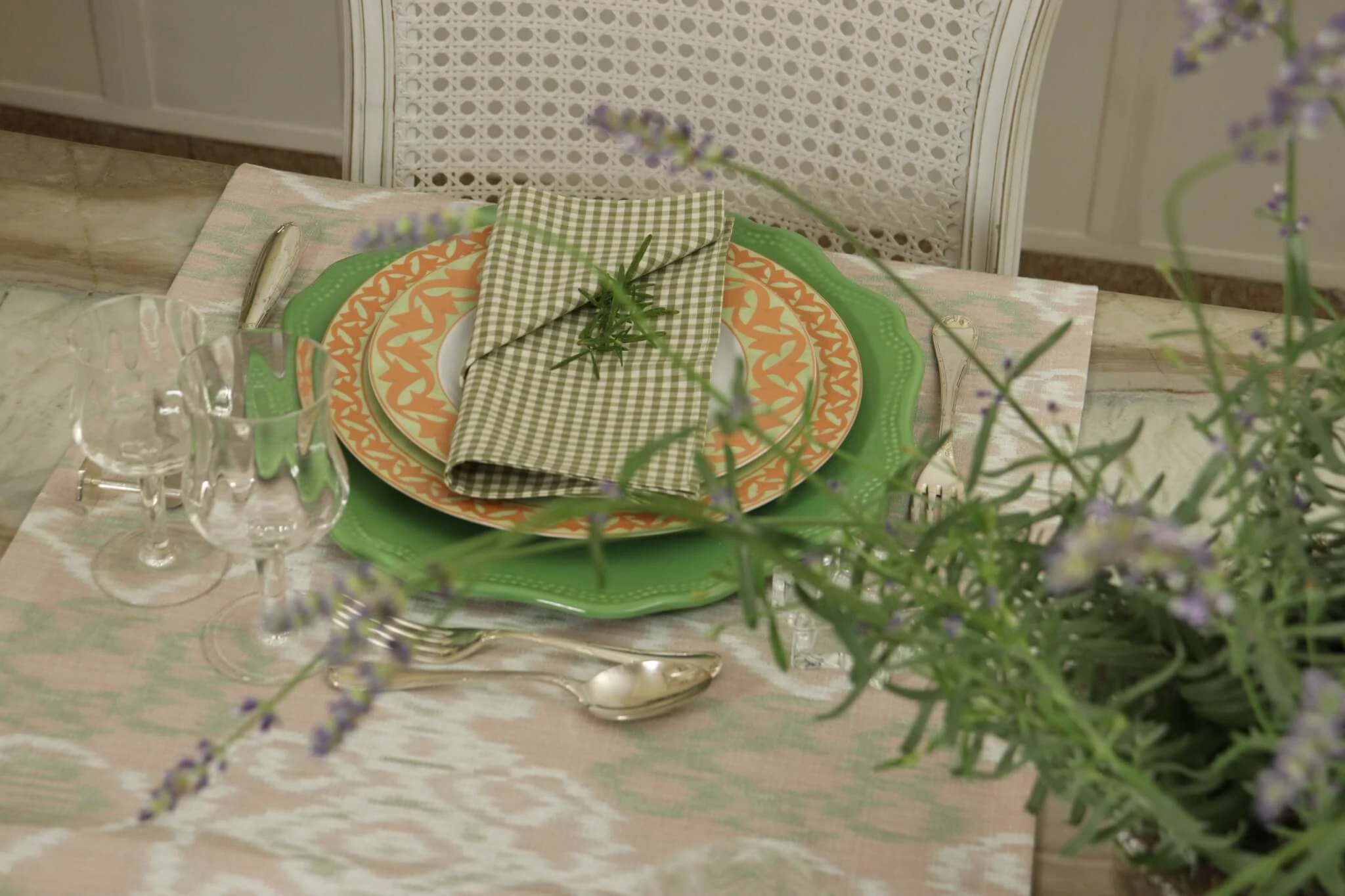 Mesa-posta-com-lavanda-em-primeiro-plano-porcelana-decorada-em-tons-de-coral-e-verde-guardanapos-vichy-e-composicao