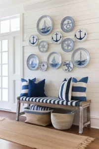 Parede decorada com pratos azuis e brancos em estilo coastal acima de banco com almofadas listradas e fibras naturais.