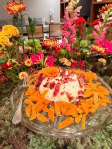 Queijo-cremoso-decorado-com-damascos-secos-em-composicao-gastronomica-cercada-por-flores-vibrantes